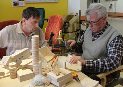 Bewohner des Altenheim Schweikershain basteln gemeinsam einen Zug aus Holz